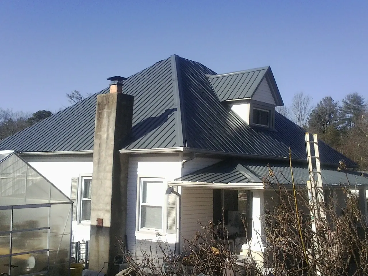 Dark blue standing seam metal roof on a white farmhouse with dormer — Slate & Tile Roof Repair by Roofing Brothers in Boring