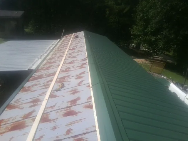 Old rusted panels beside newly installed green metal roofing — Wind Damage Roof Repair by Roofing Brothers in Boring