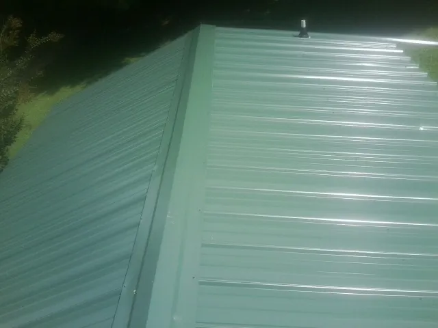 New green metal panels meeting at the ridge of a roof — Flat Roof Repair work by our crew in Boring
