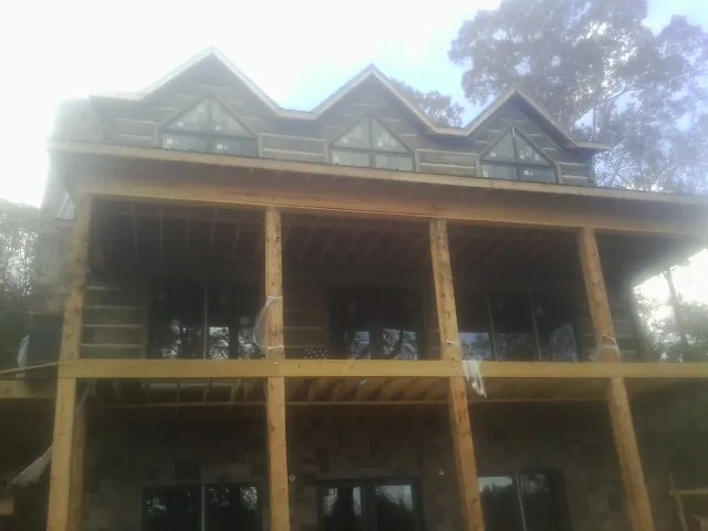 Dormers and porch framing on a large log home under construction — Roof Coating work by our crew in Boring