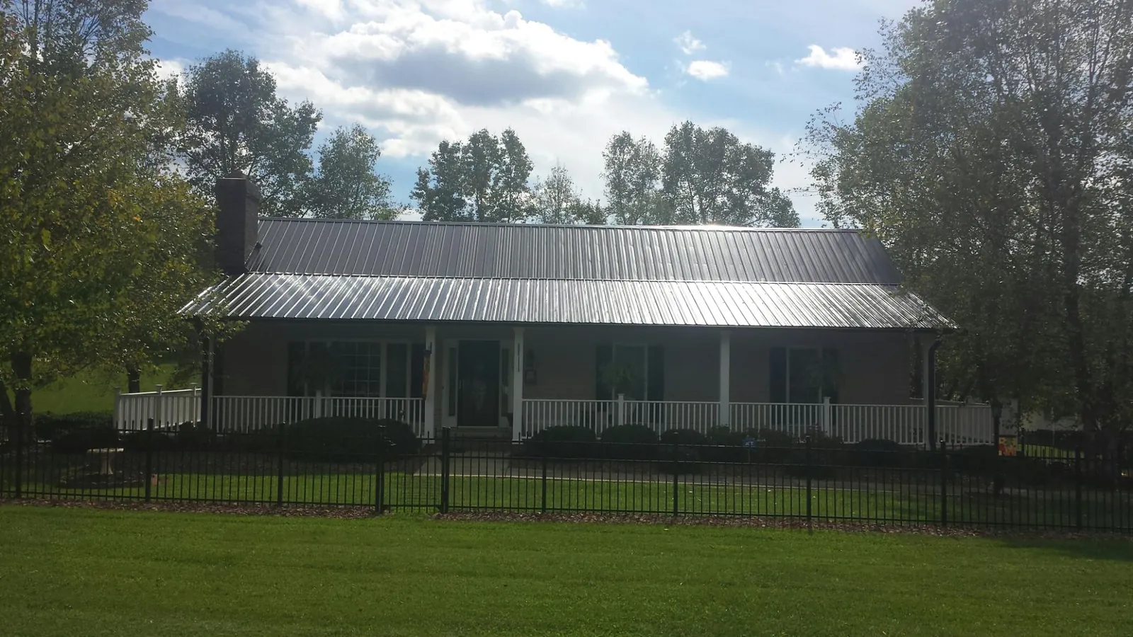 Gray metal roof on a brick ranch with a full width front porch — Gutter Guard Installation work by our crew in Boring